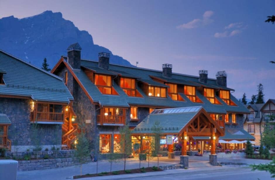Stone lodge exterior with timber entry and mountain peak backdrop
