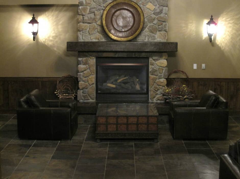 Stone-clad gas fireplace with leather armchair seating and slate tile flooring
