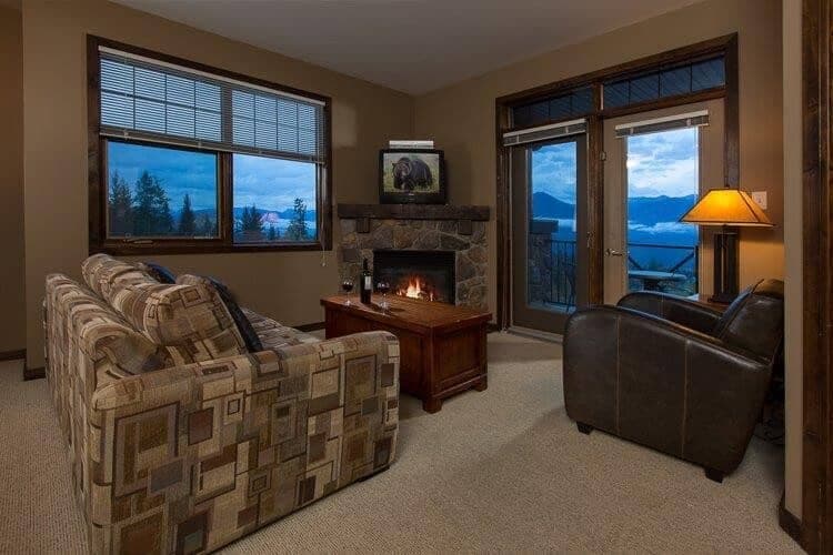 Living area with stone fireplace and private balcony access with mountain views