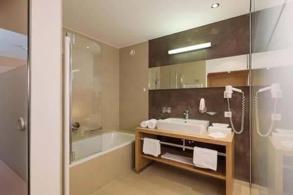 Bathroom with bathtub, walk-in shower, and wall-mounted hair dryer