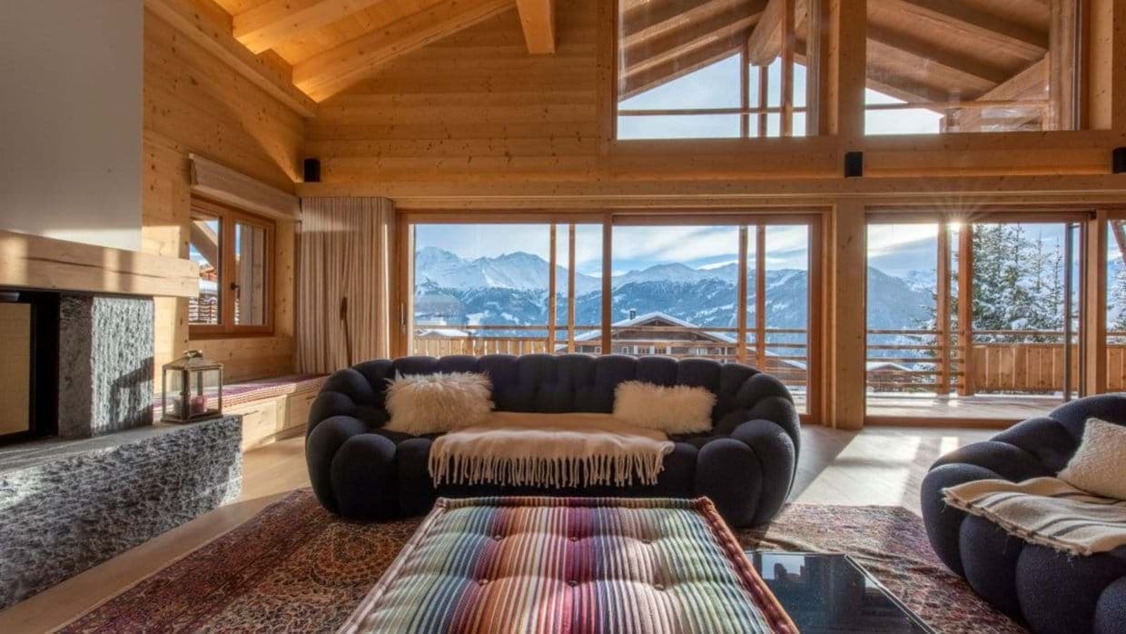 Living area with stone fireplace and floor-to-ceiling mountain views