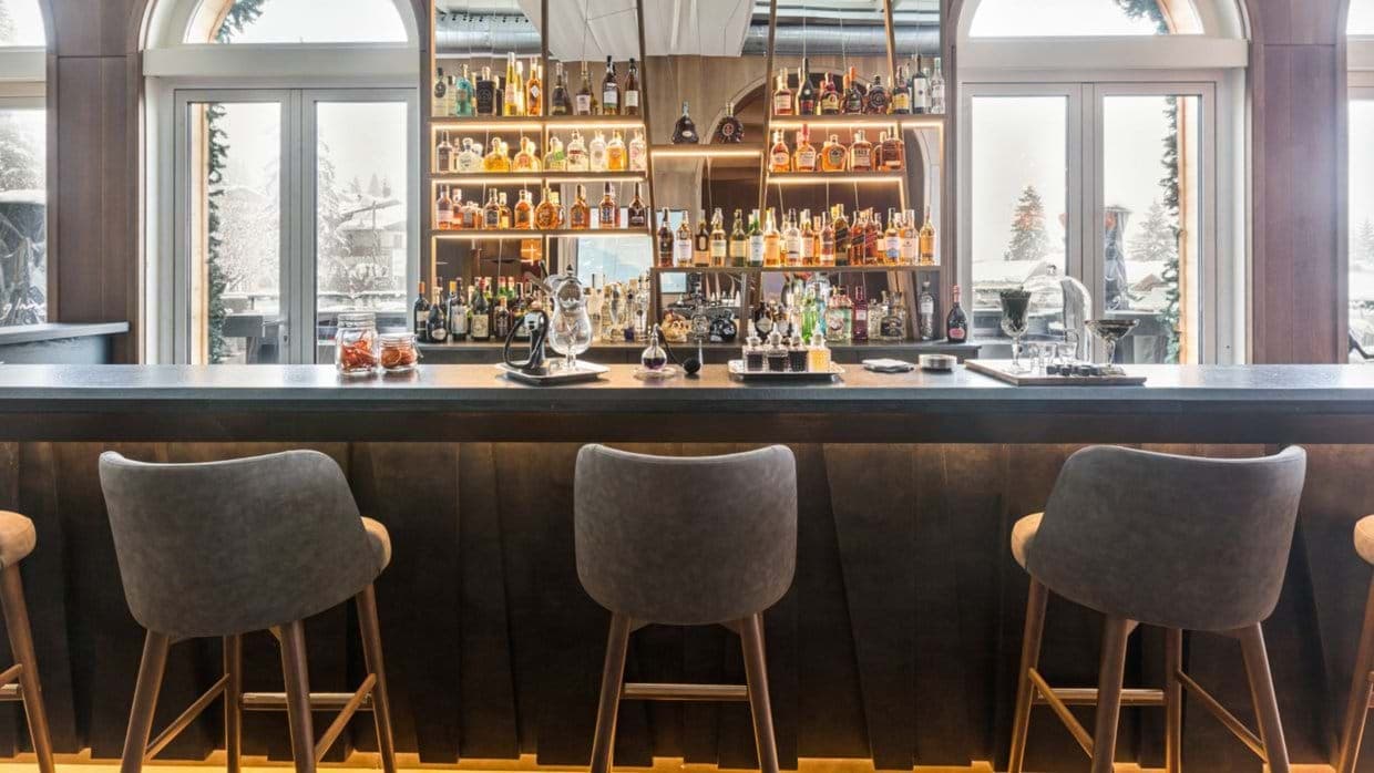 Private bar with upholstered seating and mountain views through French doors