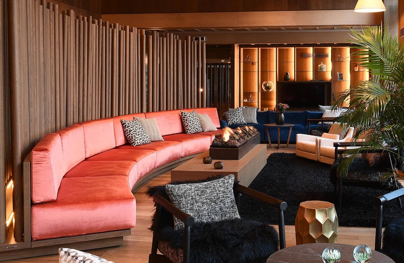 Lounge area with curved velvet sectional, gas fireplace, and media wall