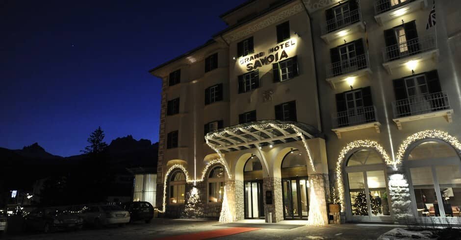 Hotel entrance at night with illuminated facade and mountain peak backdrop