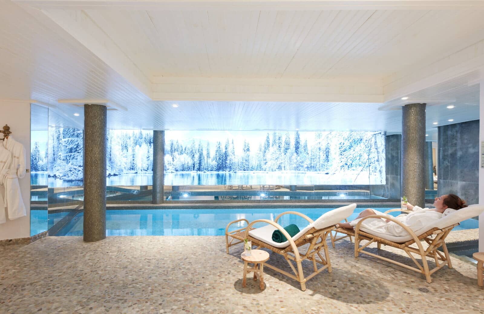 Indoor pool with lounge seating and floor-to-ceiling winter views