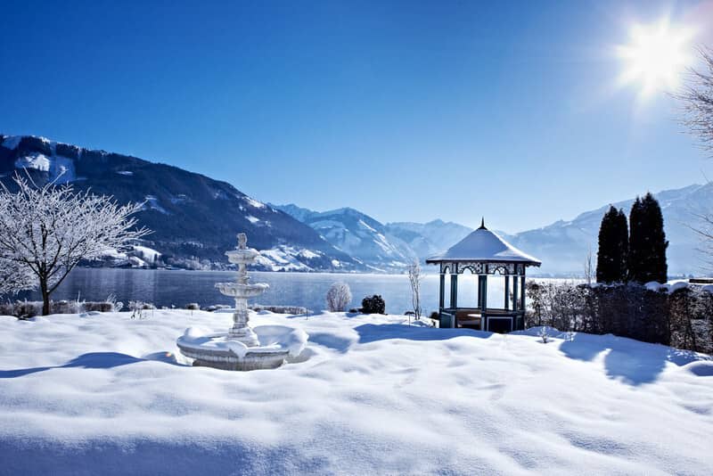 Snow-covered garden with lakefront gazebo and mountain views