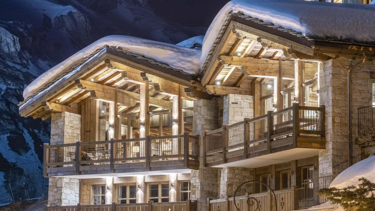 Chalet exterior with timber balconies and mountain views at night