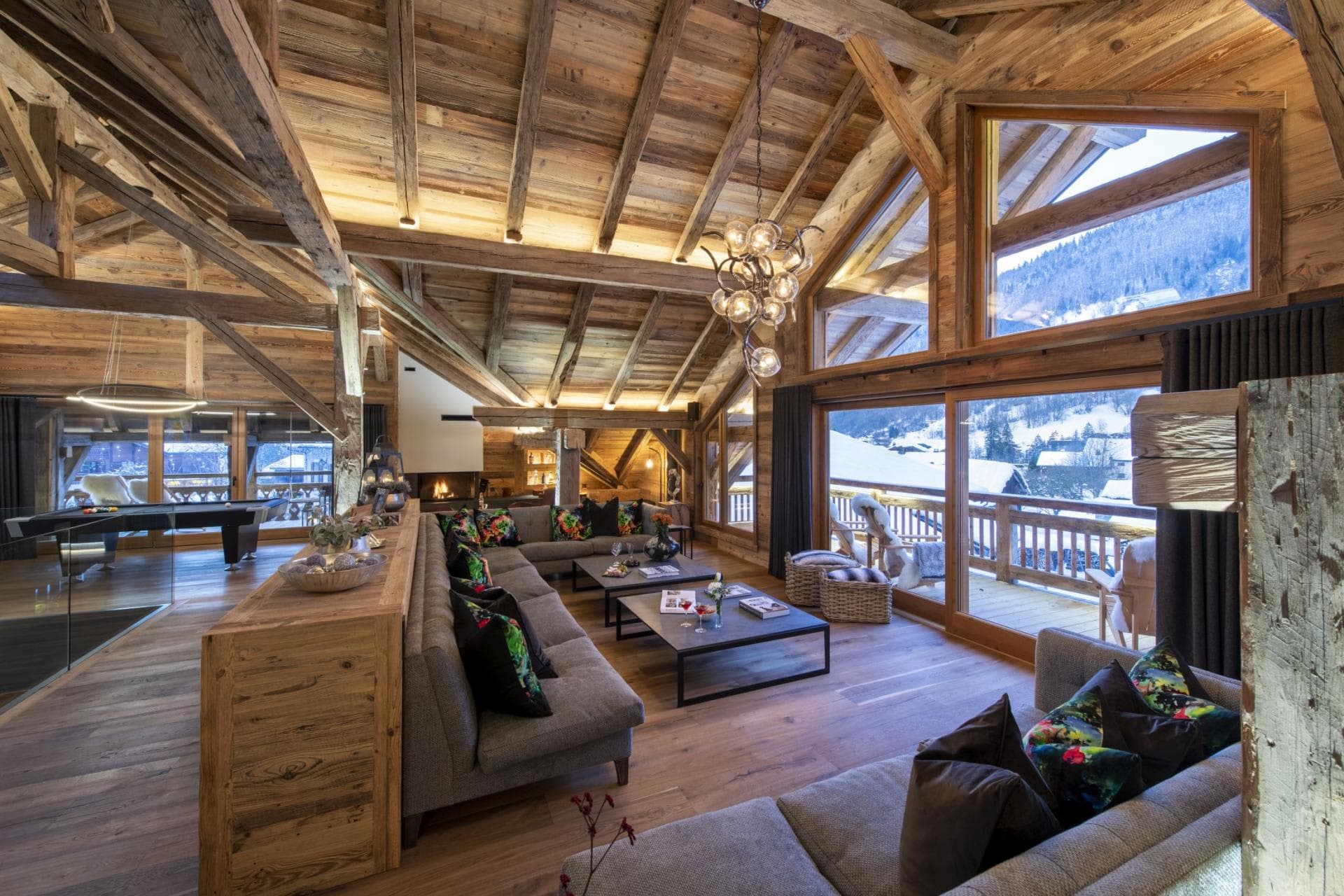 Open-plan living area with vaulted ceilings, pool table, and mountain-view balcony