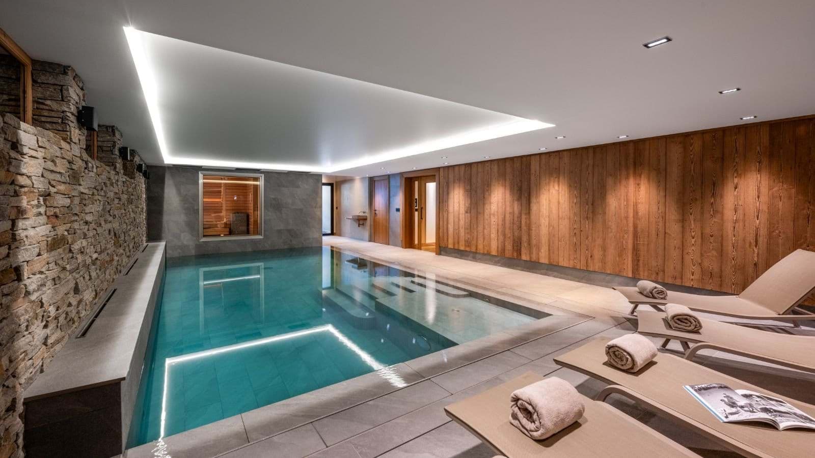 Indoor pool area with integrated sauna and poolside lounge seating