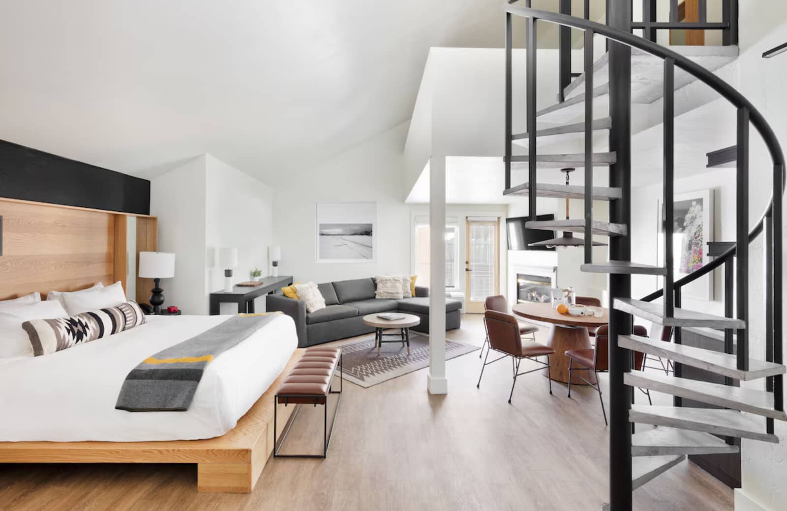 Studio loft with king bed, fireplace, and spiral staircase to upper level