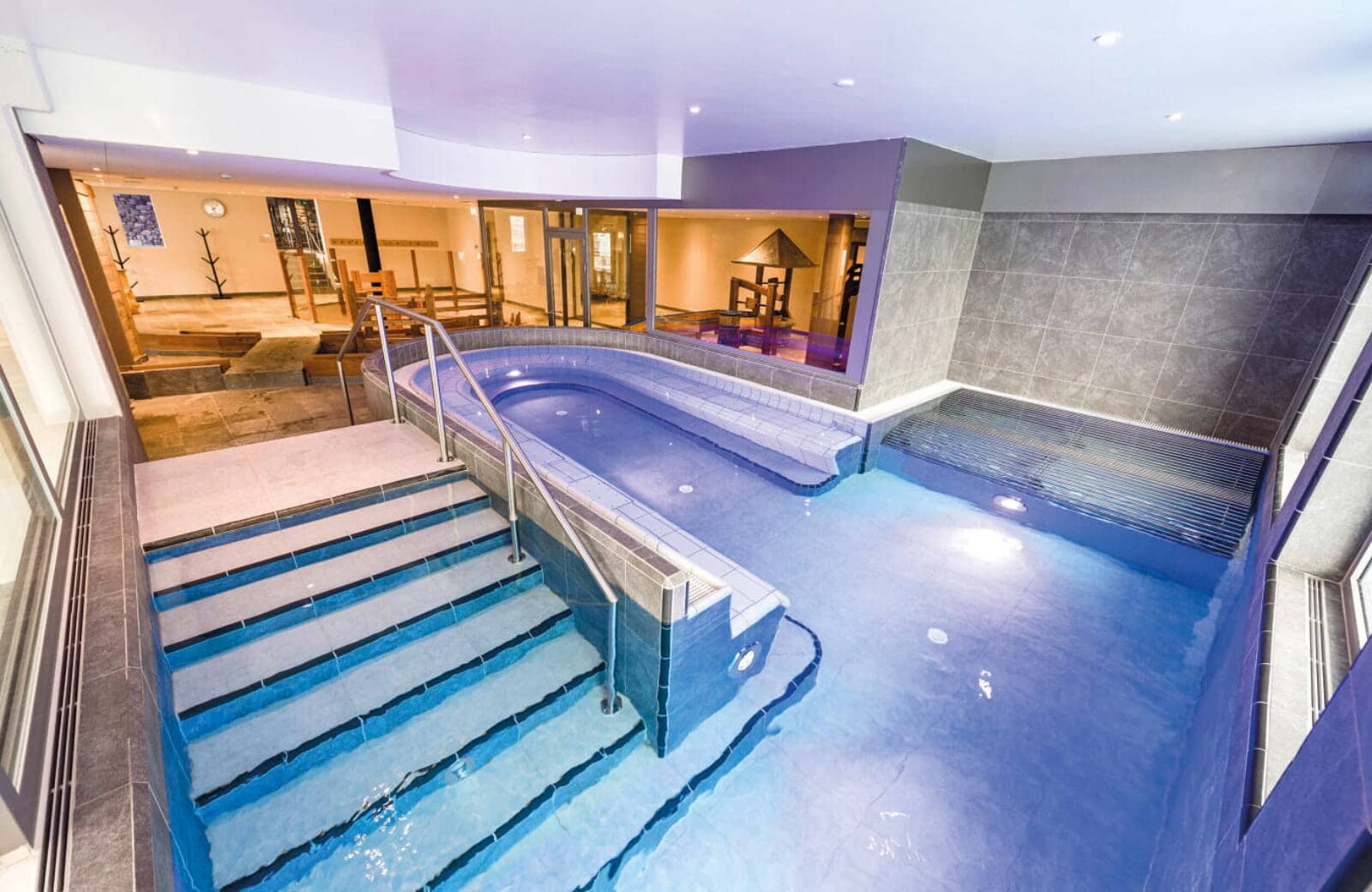 Indoor heated pool with integrated bench seating and handrail access