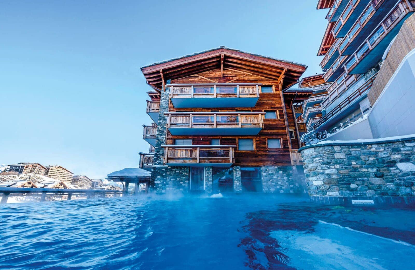 Heated infinity pool with mountain views and private chalet balconies