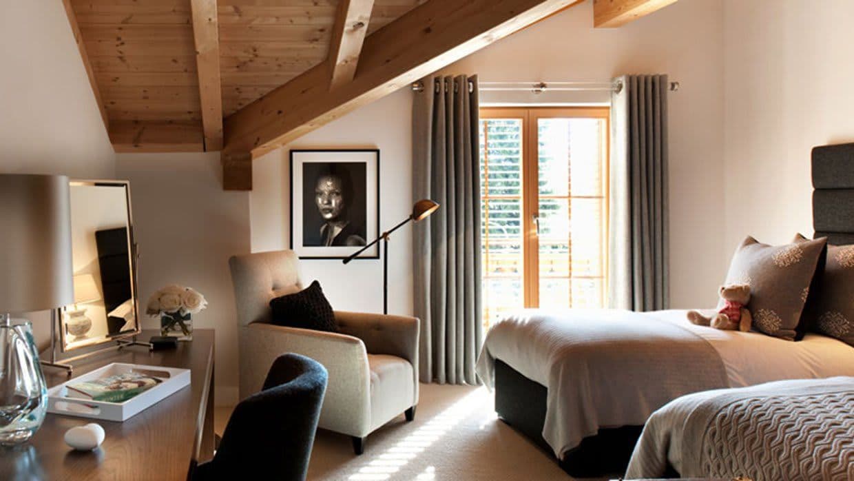 Bedroom with twin beds, vaulted wood-beam ceiling, and desk