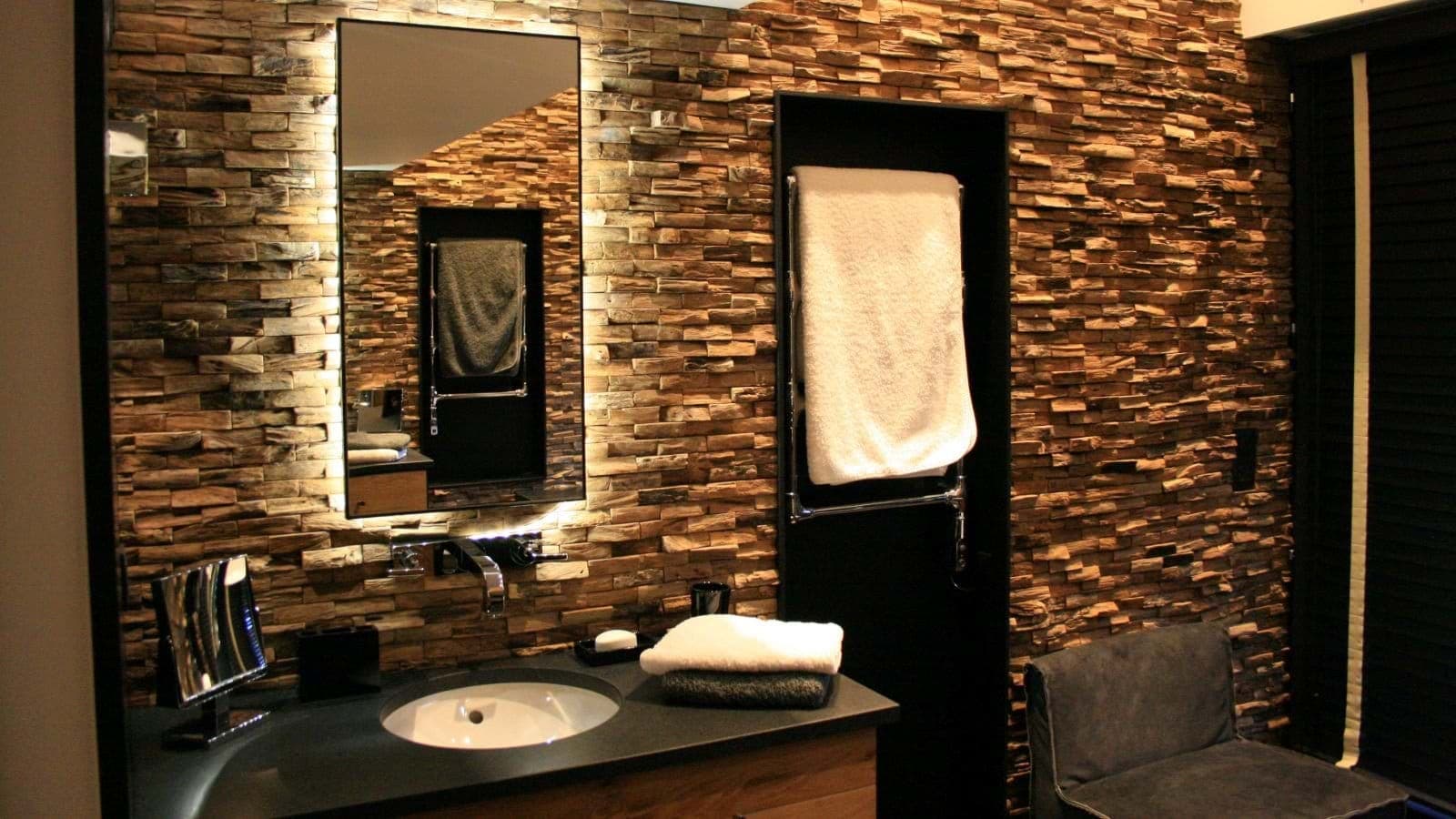 Bathroom featuring stacked stone accent wall and heated towel rack