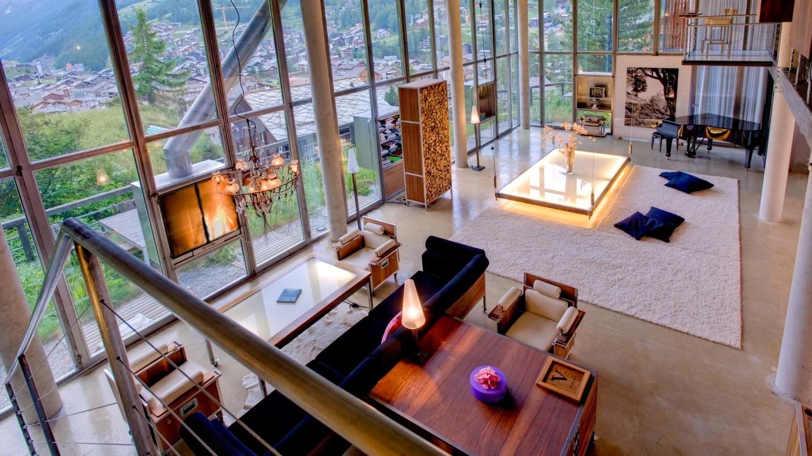 Open-plan living area with grand piano and floor-to-ceiling alpine views