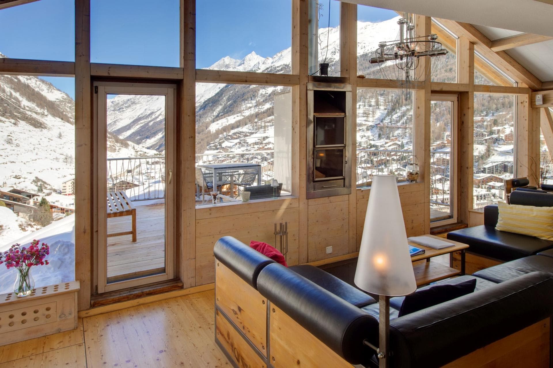 Living area with floor-to-ceiling windows, wood-burning stove, and alpine valley views