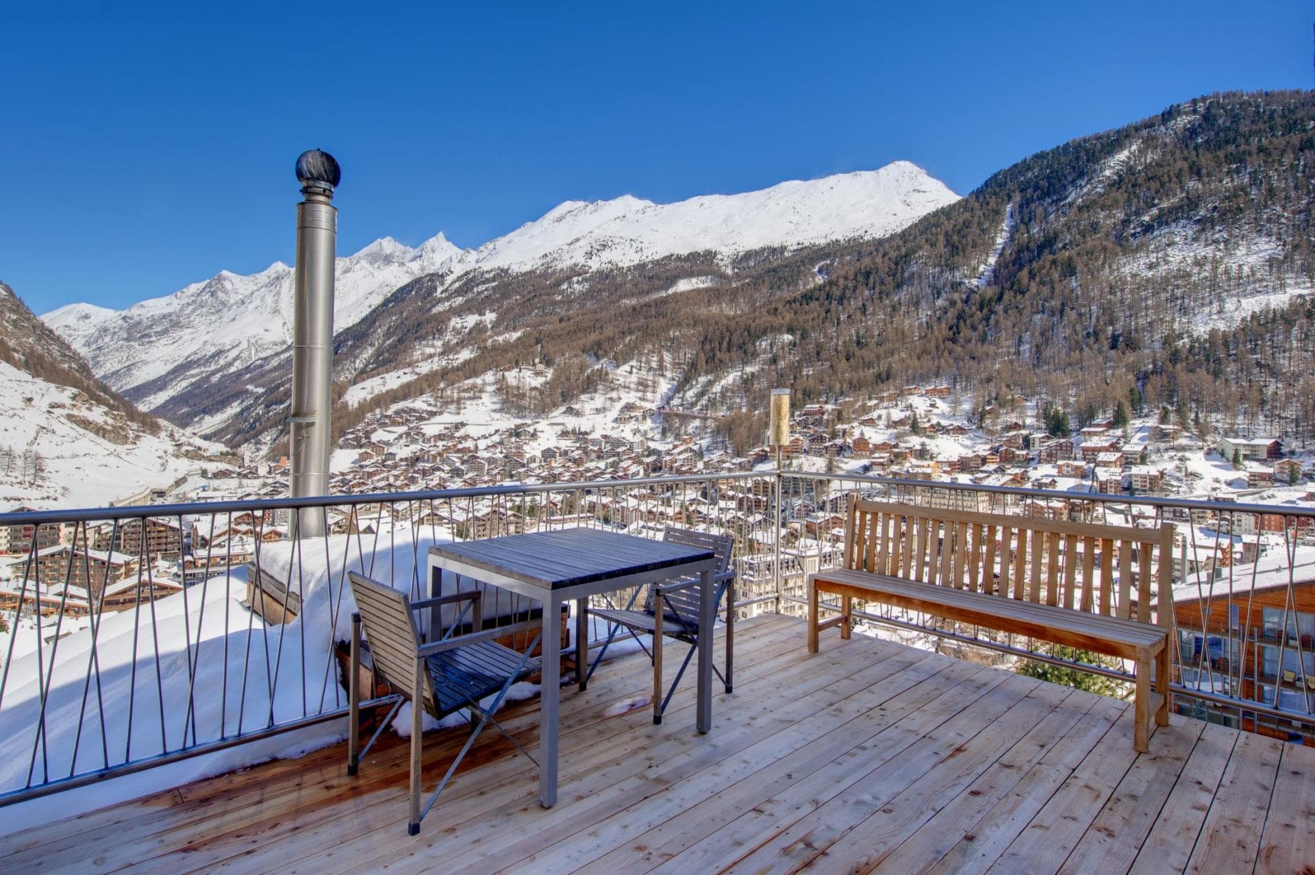 Private timber balcony with dining table and panoramic Alpine village views