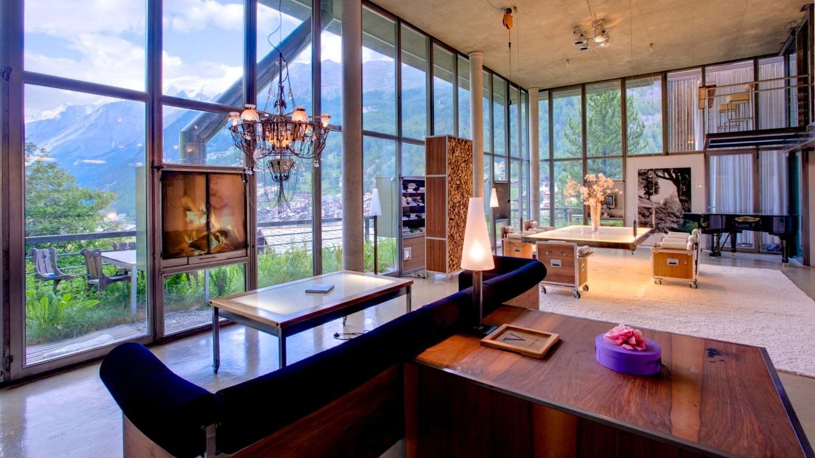 Living room with floor-to-ceiling glass, wood fireplace, and mountain views