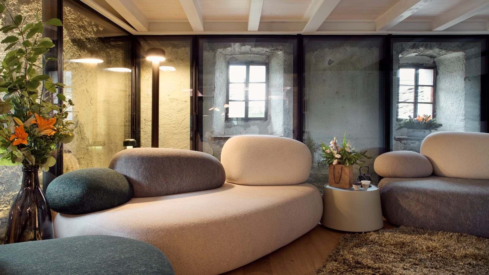 Lounge area with modular seating and original stone walls behind glass