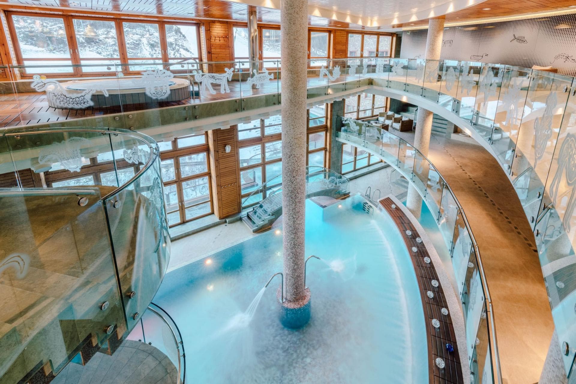 Indoor pool with upper-level hot tub and snowy mountain views
