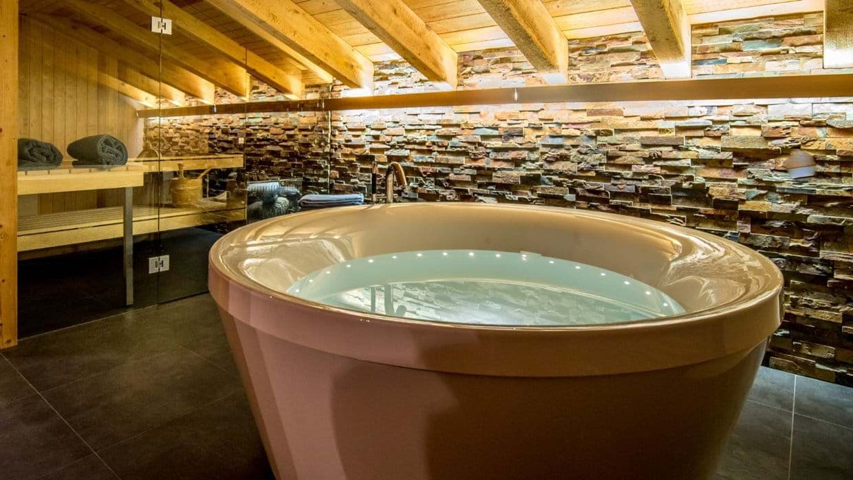 Spa area with circular soaking tub and adjacent glass-enclosed sauna