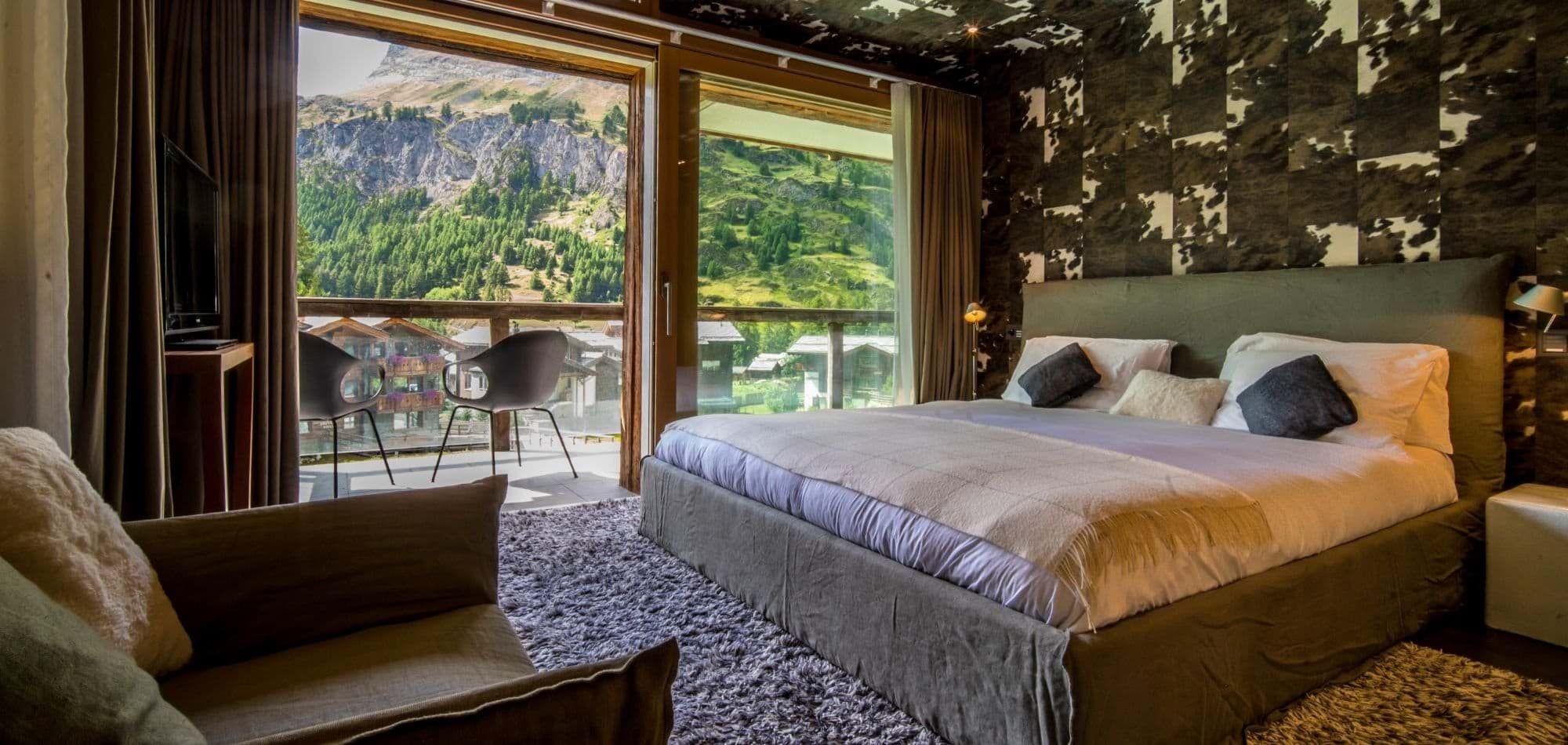 Primary bedroom with king bed and private balcony mountain views