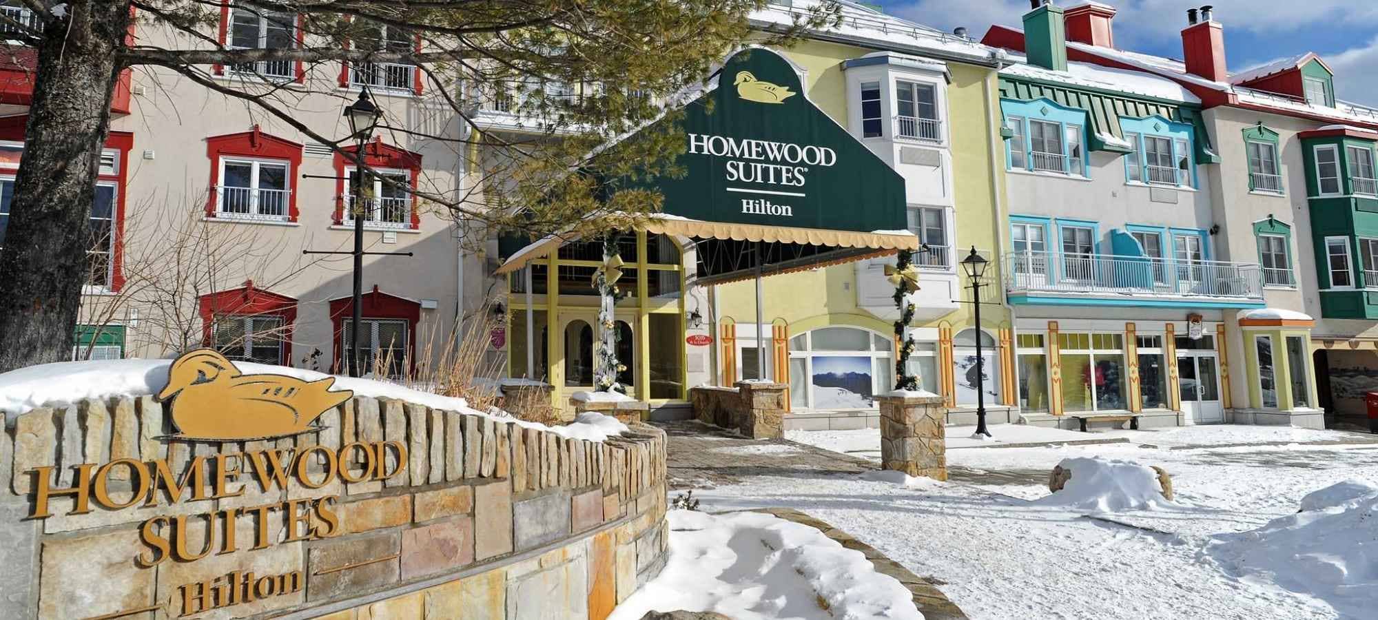 Hotel exterior with covered entrance and stone signage in pedestrian village
