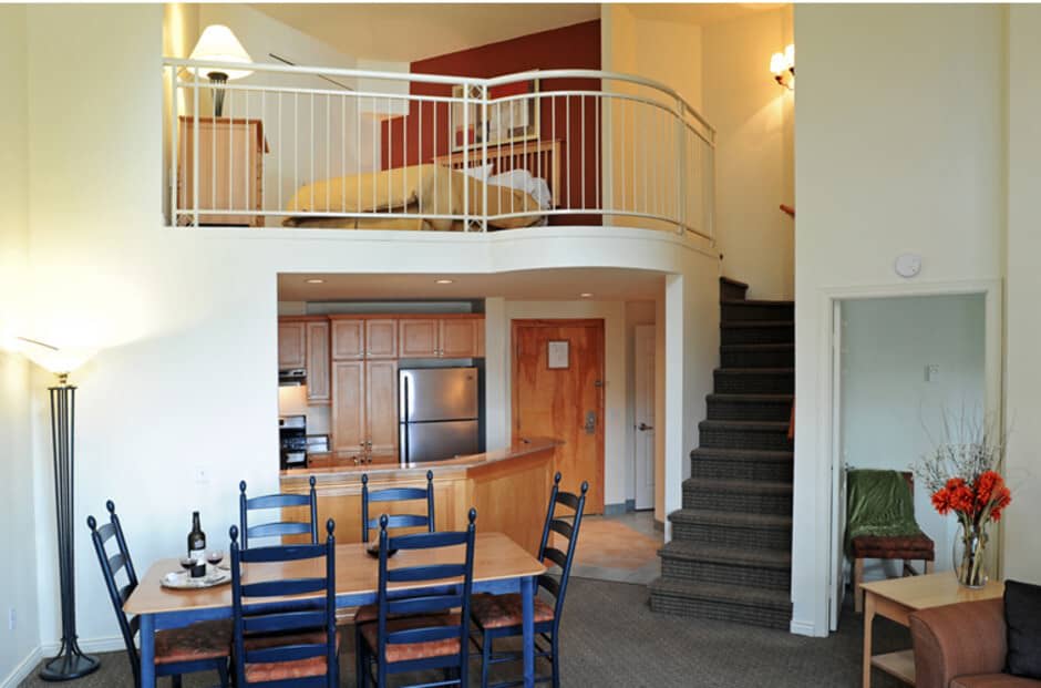 Loft bedroom overlooking dining area and kitchen with full-size refrigerator