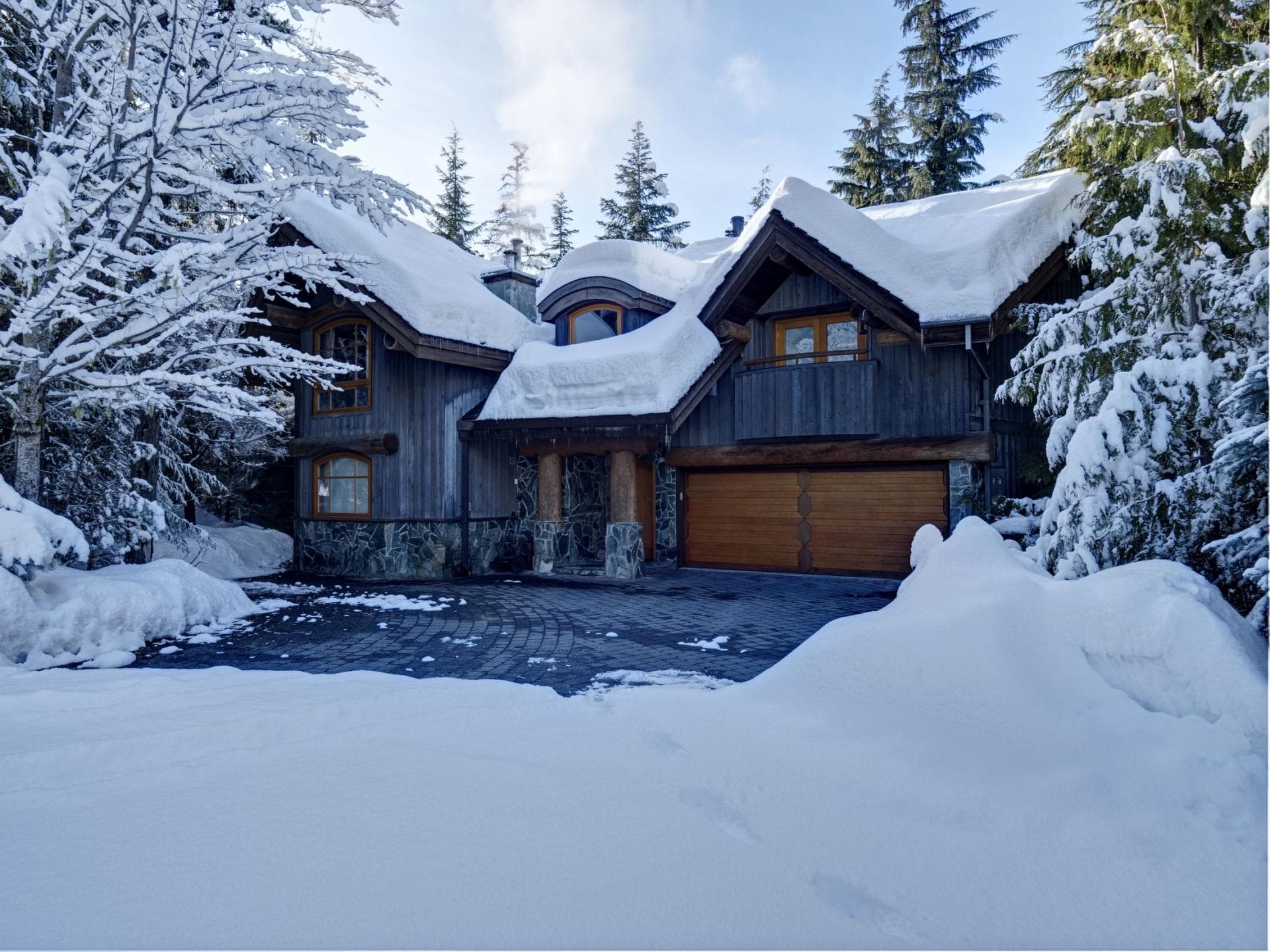 Chalet exterior featuring two-car heated garage and private stone driveway