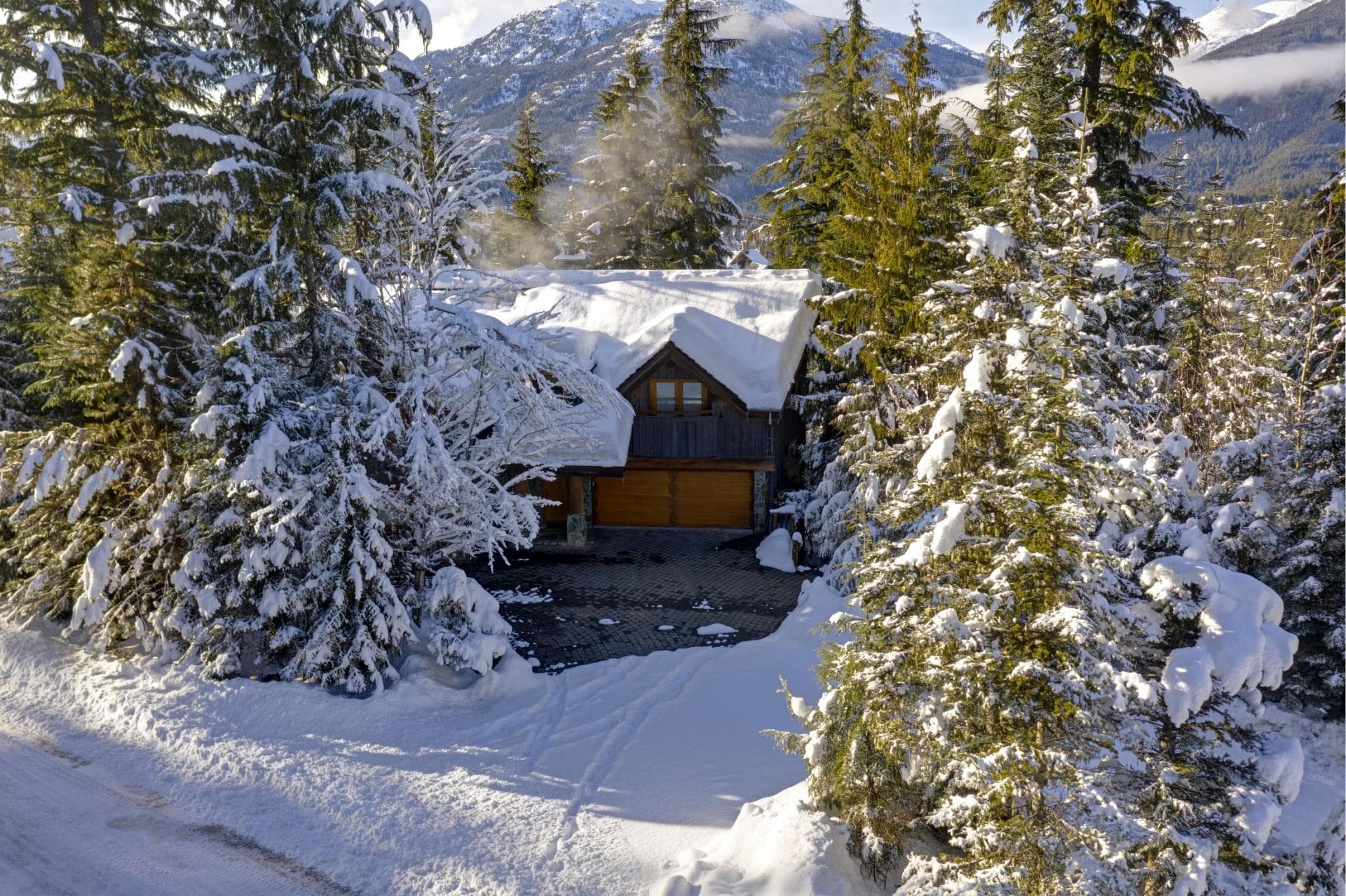 Snow-covered chalet exterior with two-car garage and mountain views