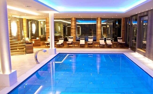Indoor heated pool with waterfall feature and lounge seating for 8