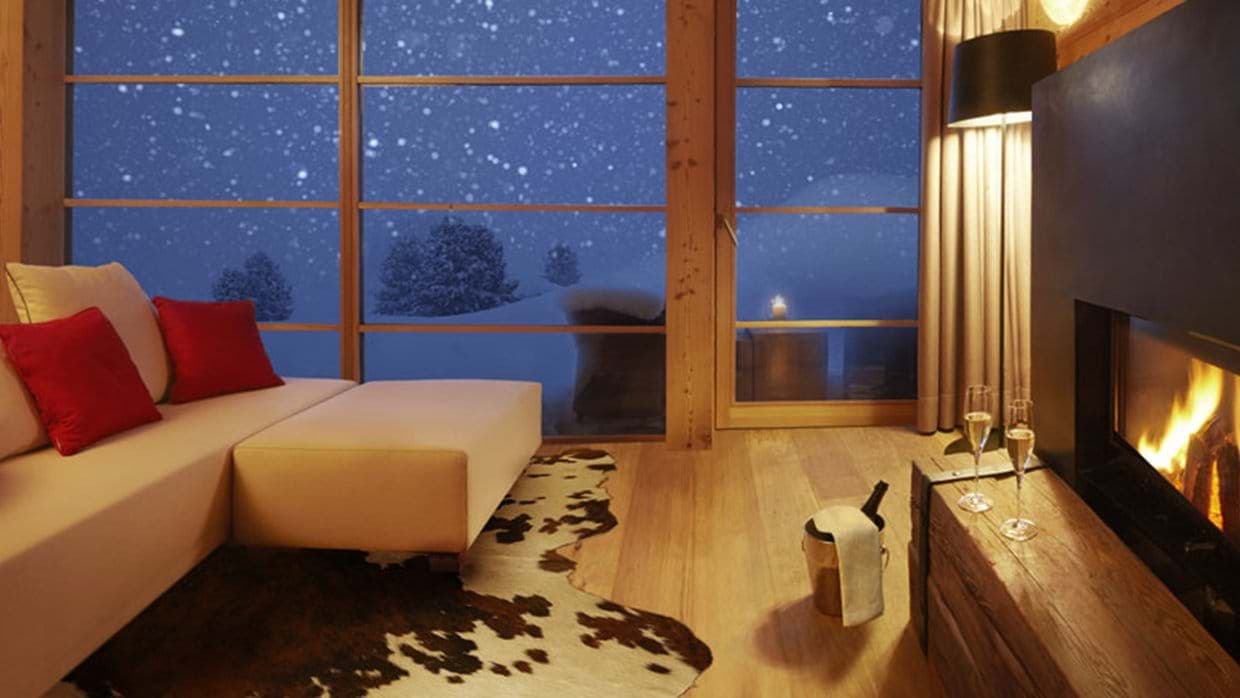 Living area with wood-burning fireplace and floor-to-ceiling snow views