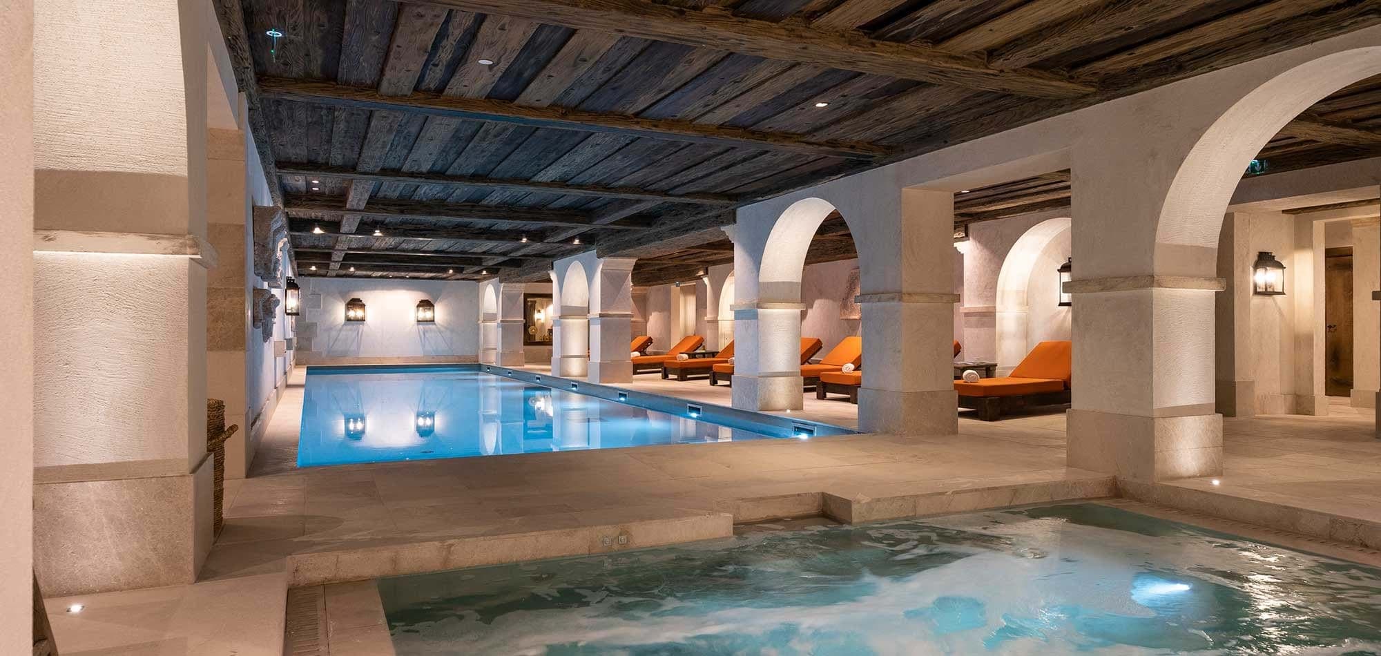 Indoor pool and hot tub with lounge seating and reclaimed wood ceilings