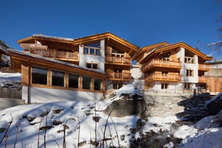 Chalet exterior with multiple private balconies overlooking a mountain stream