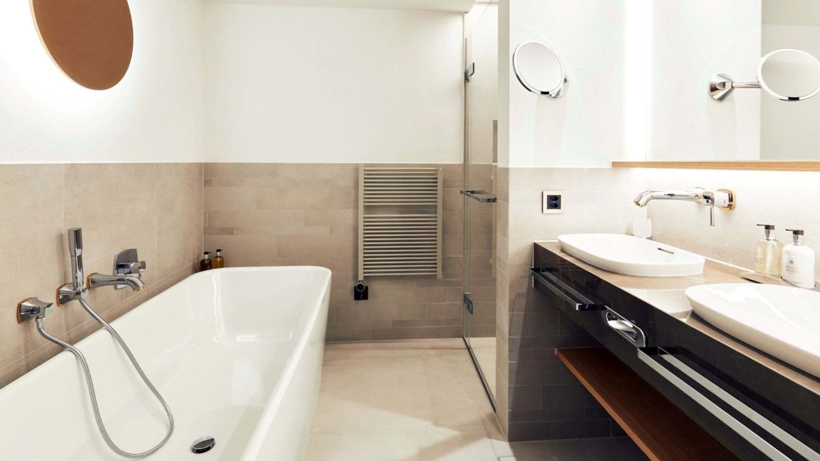 Bathroom with soaking tub, dual vanity, and heated towel rack