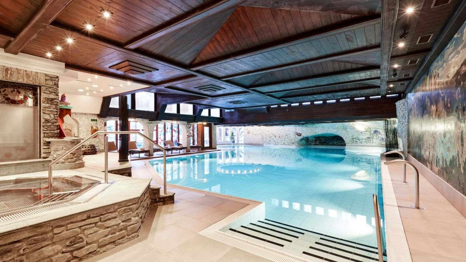 Indoor heated pool and hot tub with timber ceiling and stone accents