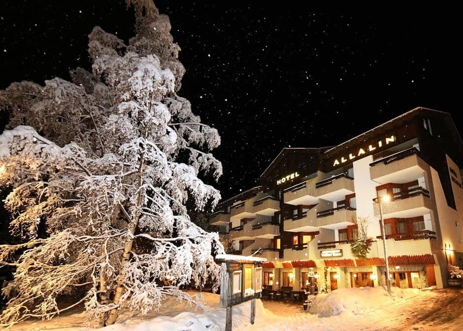 Hotel exterior at night with private balconies and street-level dining terrace