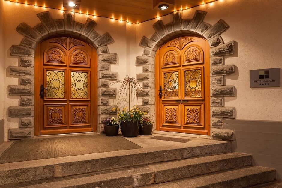 Main entrance with hand-carved wood doors and stone archways