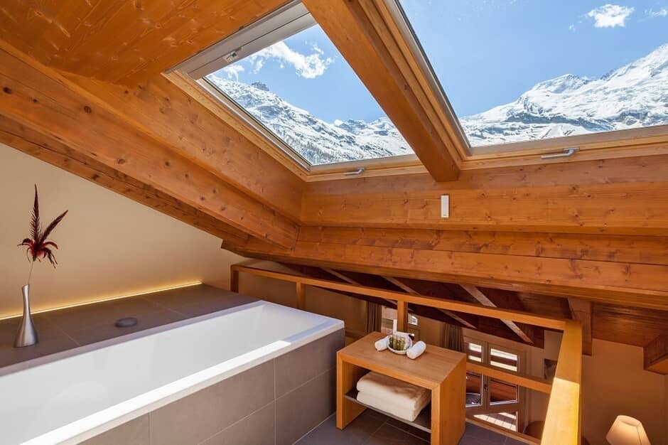 Loft bathroom with soaking tub and skylight views of snow-capped mountains