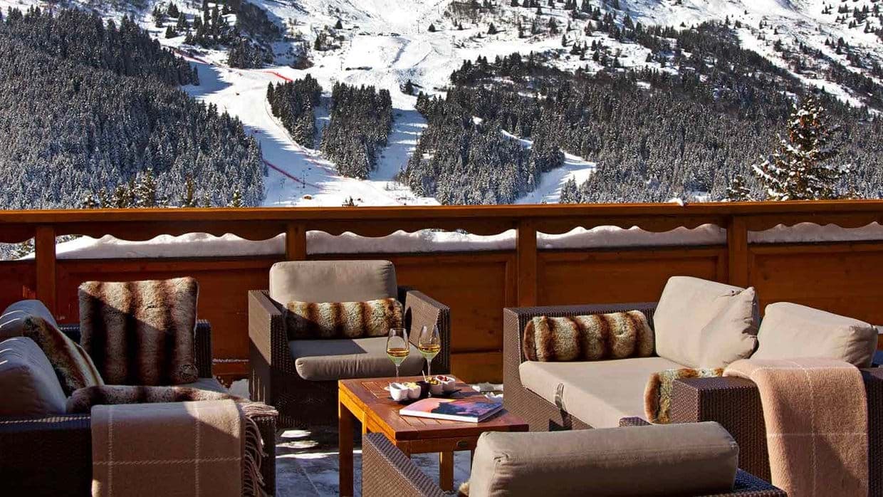 Private balcony with lounge seating overlooking active ski slopes