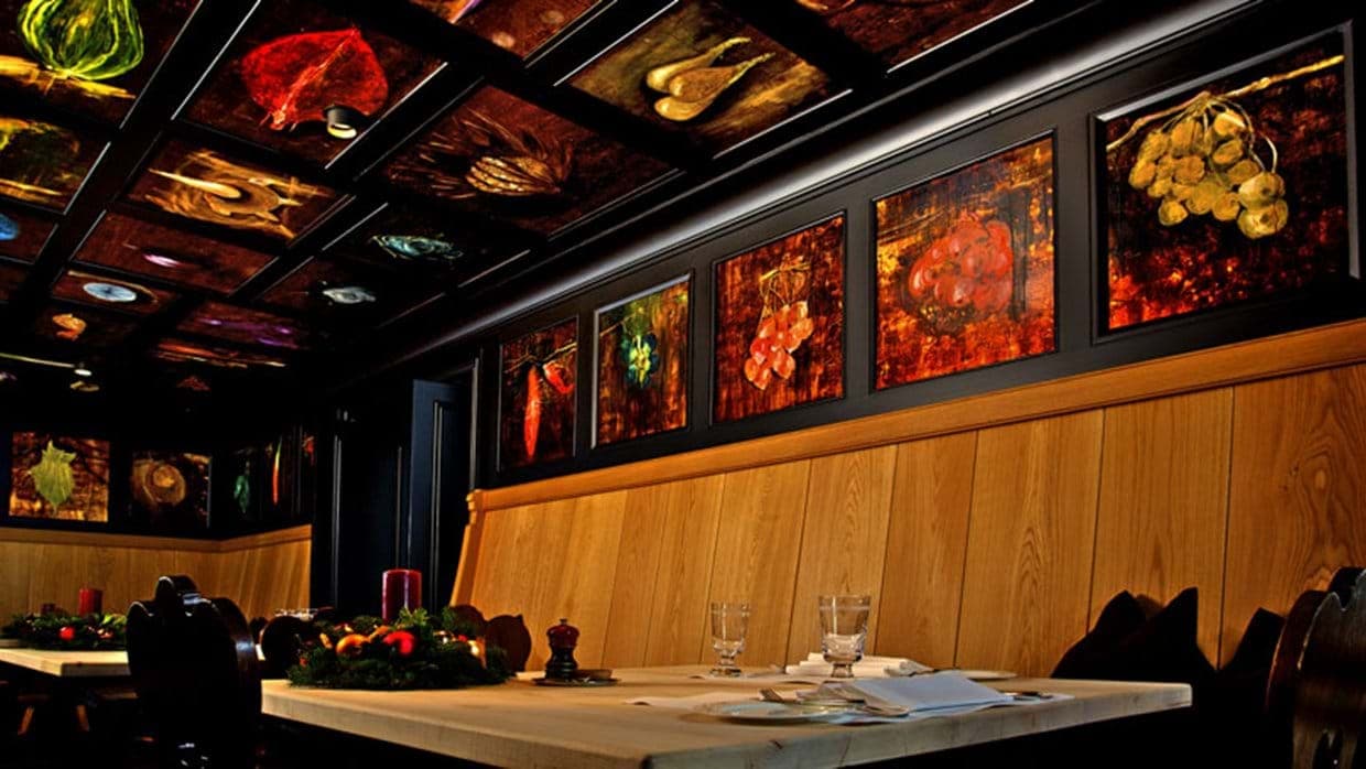 Dining area with wood banquet seating and botanical ceiling panels