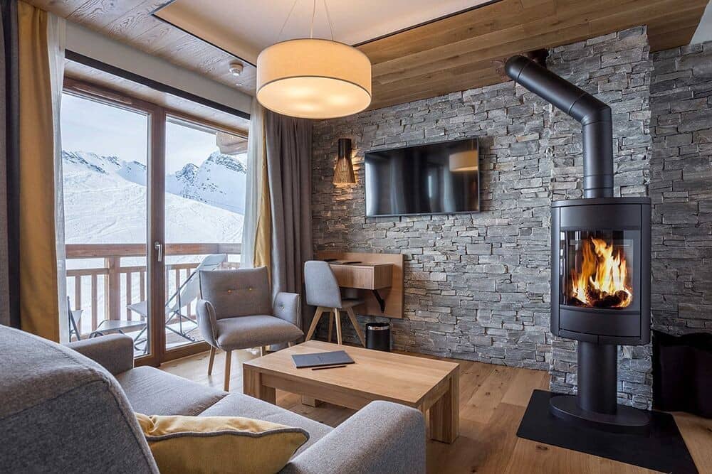 Living area with wood-burning stove, workspace, and balcony access to mountain views
