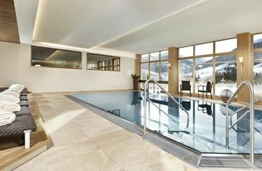Indoor heated pool with mountain views and lounge seating