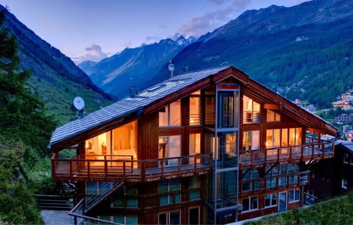 Chalet exterior featuring a glass elevator and private balconies with alpine views