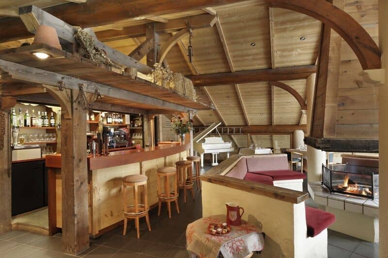 Timber-framed bar area with wood-burning fireplace and grand piano
