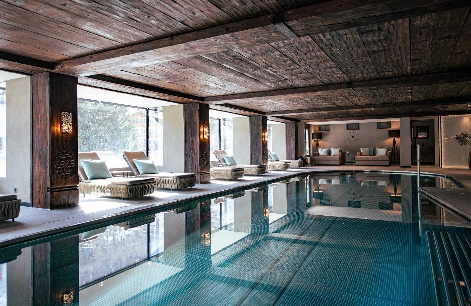 Indoor pool with loungers, floor-to-ceiling windows, and reclaimed wood ceiling