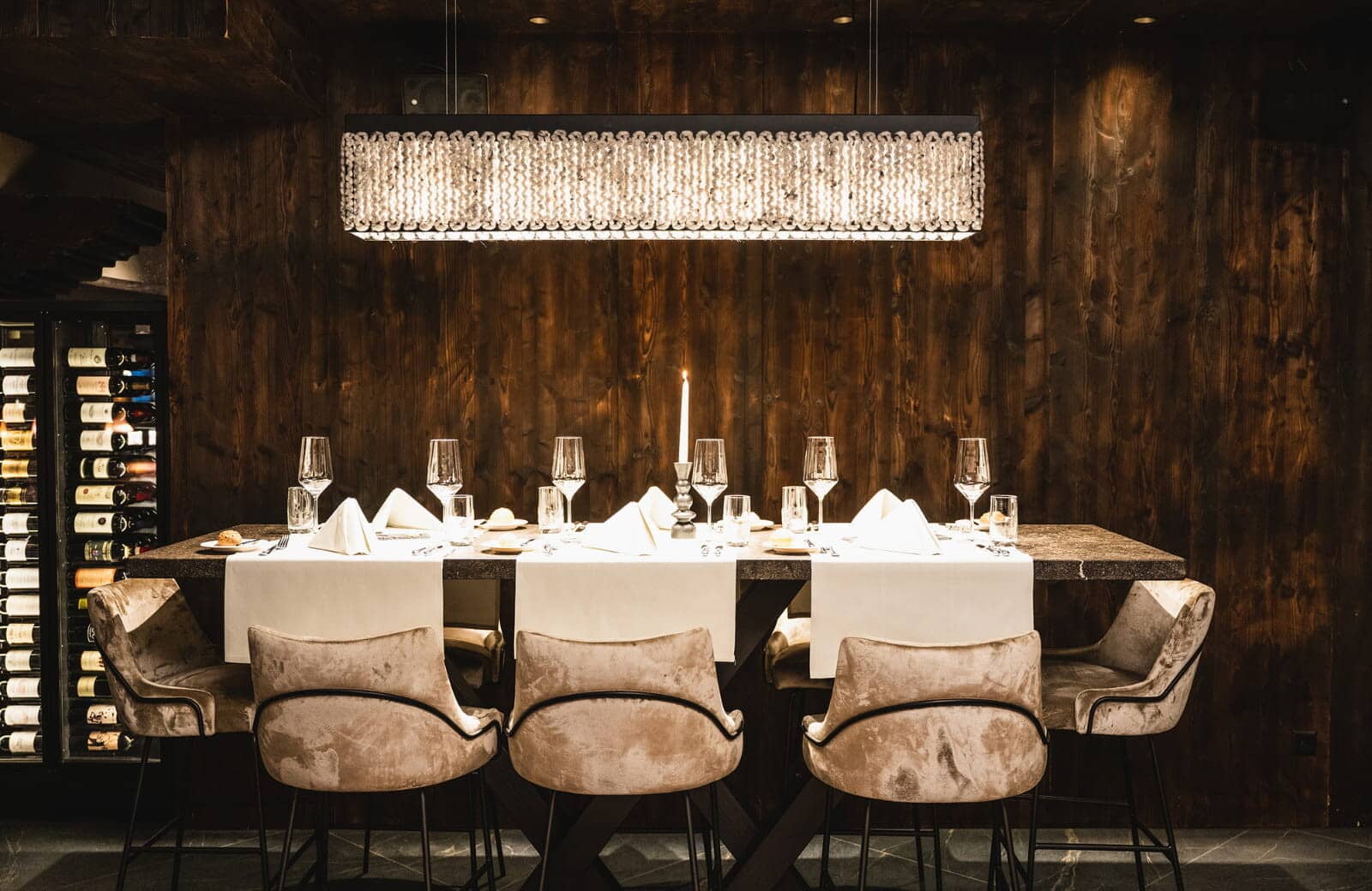Dining area with velvet seating and glass-enclosed wine cellar