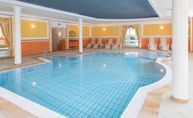 Indoor heated pool with poolside lounge chairs and step entry