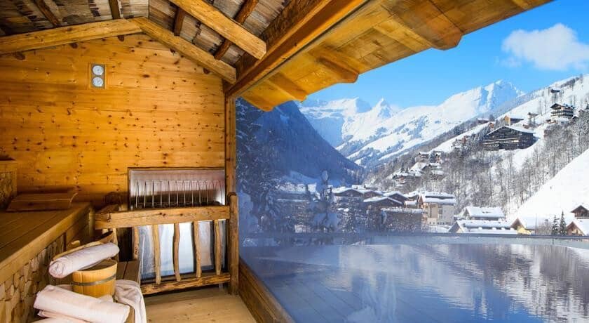 Wood-paneled sauna and heated infinity pool with alpine valley views