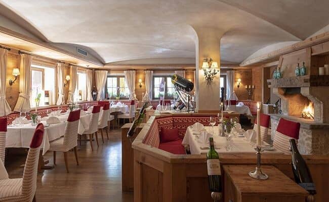Dining room with wood paneling, banquet seating, and open stone fireplace